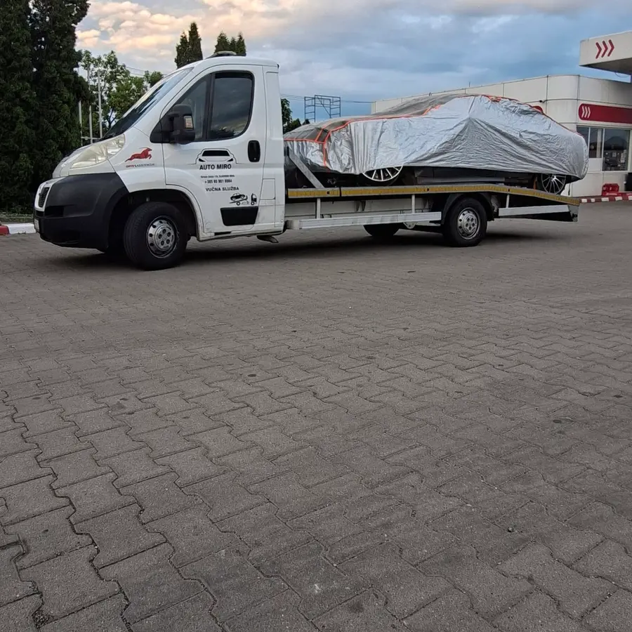 Kamion AUTO MIRO s natpisom na vratima i automobilom pod zaštitnim pokrivačem