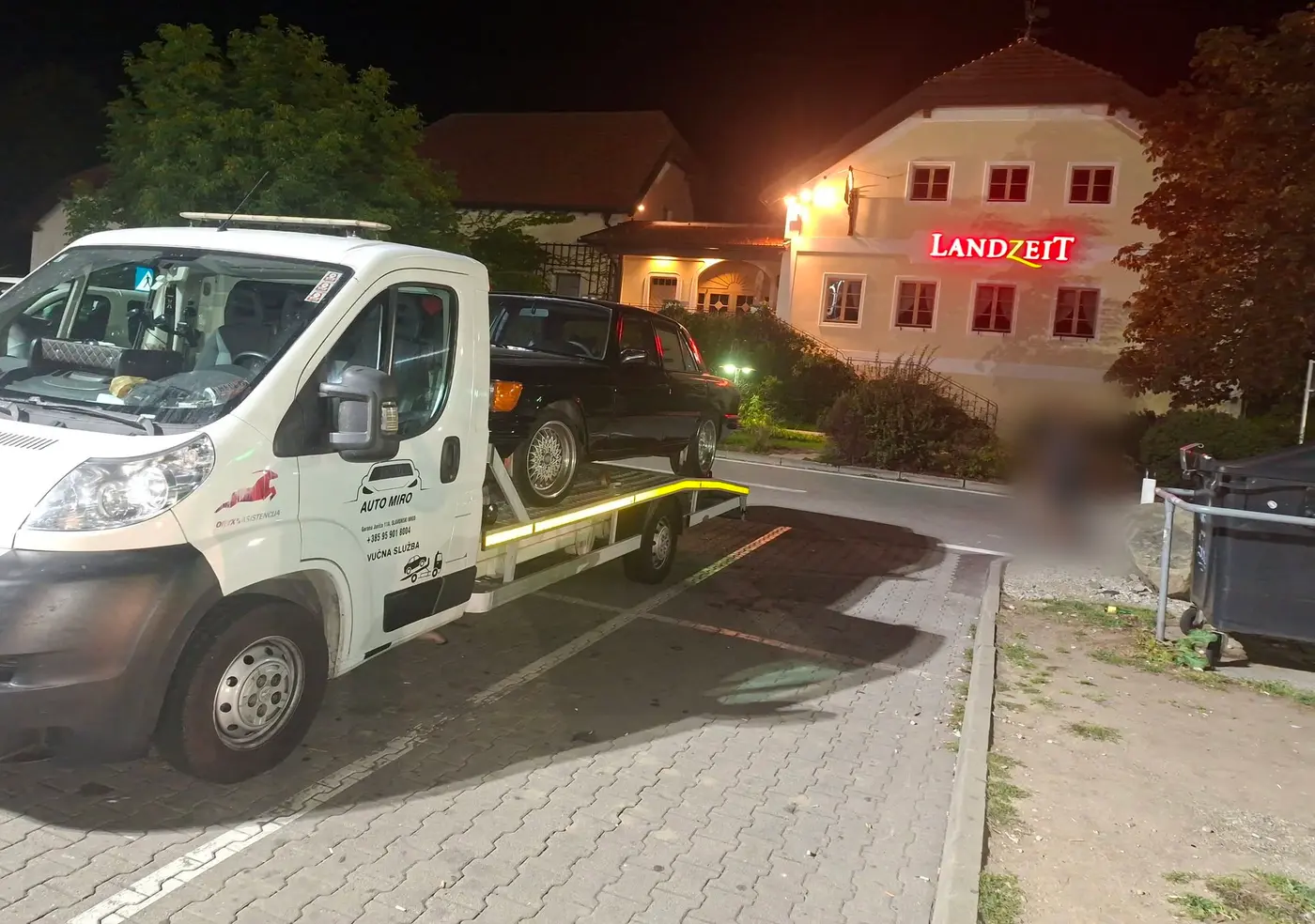 Kamion AUTO MIRO s utovarenim crnim automobilom noću ispred gostionice u Austriji